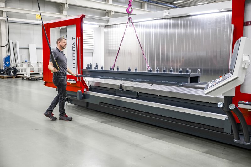 5-Achs-CNC-Bearbeitungszentrum TILTENTA 7-3600 NEO mit Schwenkspindel während der Kranbeladung eines Bauteils durch den Bediener