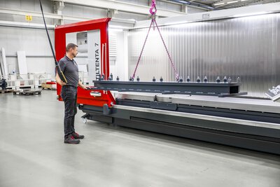 5-Achs-CNC-Bearbeitungszentrum TILTENTA 7-3600 NEO mit Schwenkspindel während der Kranbeladung eines Bauteils durch den Bediener