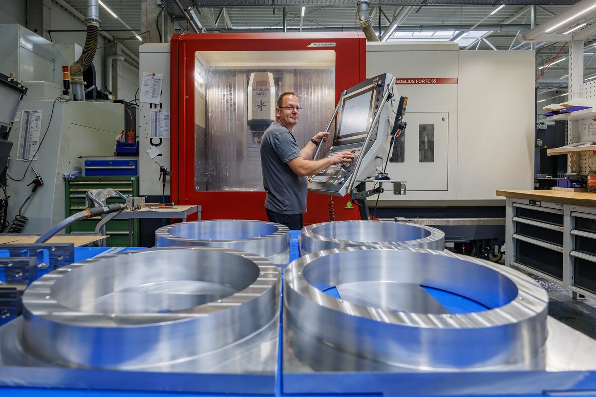 CNC Frässpezialist Jens Jakubowski an der FORTE 65 Single 1320 der ersten HEDELIUS Maschine bei Steingross mit Zwischenringen im Vordergrund