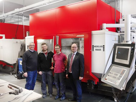 HEDELIUS Bearbeitungszentrum RS605 von schräg rechts aufgenommen. Davor stehen vier Angestellte des Unternehmens mech-tron. Die CNC-Fräse ist geschlossen