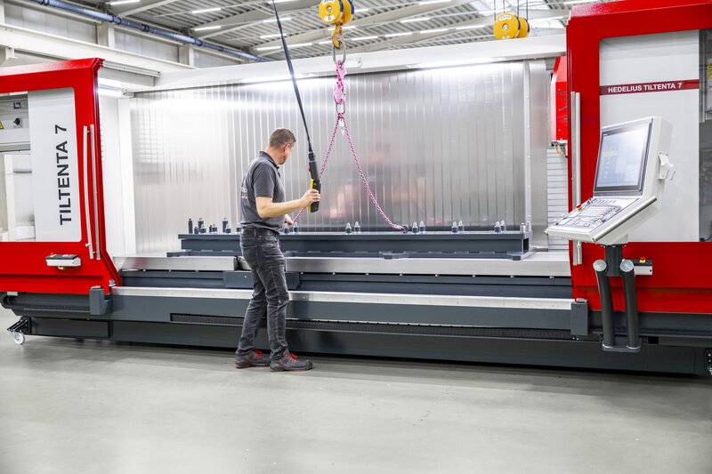 5-Achs-CNC-Bearbeitungszentrum TILTENTA 7-3600 NEO mit Schwenkspindel während der Kranbeladung eines Bauteils durch den Bediener
