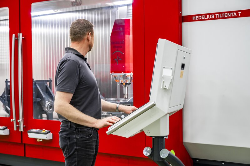 5-Achs-CNC-Bearbeitungszentrum TILTENTA 7-3600 NEO mit Schwenkspindel während der Bearbeitung und Bediener an der Steuerung
